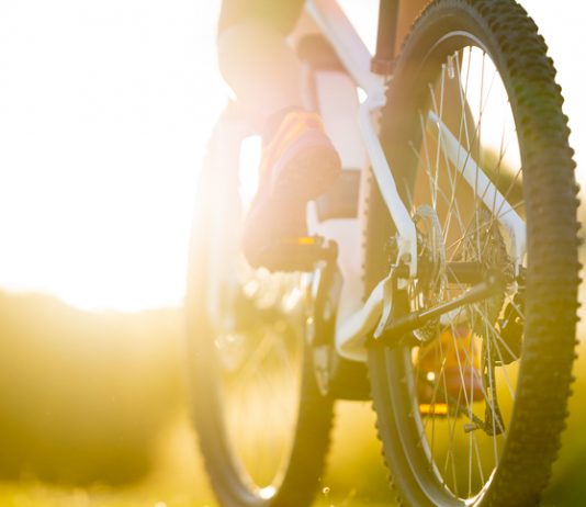 close up part of electric mountainbike sport female legs shoes summer sunny backlight rural landscape tyre