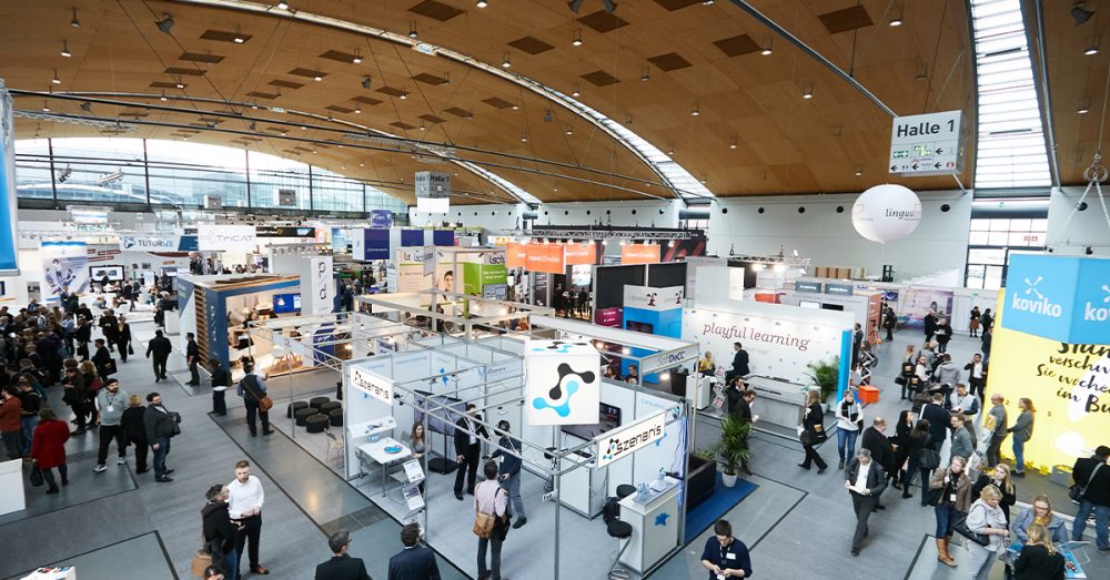 Halle mit Menschen und Ausstellern an Ständen