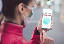 Frau schaut das Handy wo CoronaTracking zu lesen ist