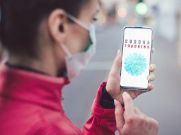 Frau schaut das Handy wo CoronaTracking zu lesen ist