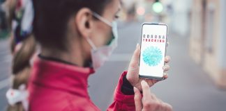 Frau schaut das Handy wo CoronaTracking zu lesen ist