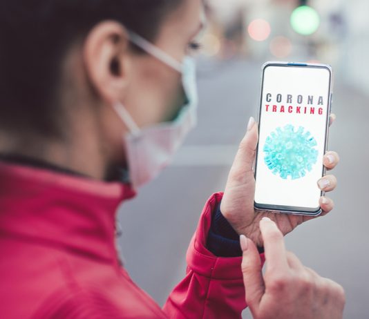 Frau schaut das Handy wo CoronaTracking zu lesen ist