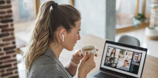 Frau sitzt zu Hause am Laptop und tirnkt einen Cafe