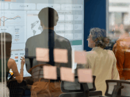 Team, das während eines Geschäftstreffens ein Brainstorming zu neuen Produkten und Dienstleistungen mit einem digitalen Display durchführt, Symbolbild für Nachfolgeplanung