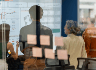 Team, das während eines Geschäftstreffens ein Brainstorming zu neuen Produkten und Dienstleistungen mit einem digitalen Display durchführt, Symbolbild für Nachfolgeplanung