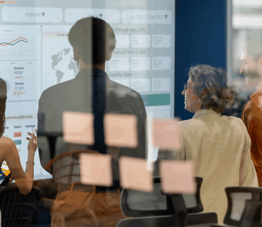 Team, das während eines Geschäftstreffens ein Brainstorming zu neuen Produkten und Dienstleistungen mit einem digitalen Display durchführt, Symbolbild für Nachfolgeplanung