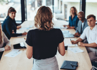Rückansicht einer Geschäftsfrau, die bei einem Meeting im Büro spricht. Weibliche Managerin, die ein Meeting mit ihrem Team im Sitzungssaal des Büros hat.