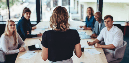 Rückansicht einer Geschäftsfrau, die bei einem Meeting im Büro spricht. Weibliche Managerin, die ein Meeting mit ihrem Team im Sitzungssaal des Büros hat.