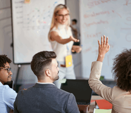 Drei Personen, die an einem Personalentwicklung Training teilnehmen, eine Person meldet sich.