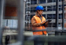 Junge Arbeiterin mit ihrem digitalen Tablet auf einer Baustelle