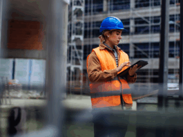 Junge Arbeiterin mit ihrem digitalen Tablet auf einer Baustelle
