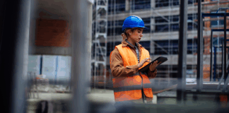Junge Arbeiterin mit ihrem digitalen Tablet auf einer Baustelle