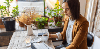 Geschäftsfrau sitzt in einem Café mit digitalem Tablet und liest Artikel. Symbolbild zum Thema Medienpräsenz