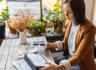 Geschäftsfrau sitzt in einem Café mit digitalem Tablet und liest Artikel. Symbolbild zum Thema Medienpräsenz