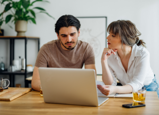 Warum der Weg zum Eigenheim so kompliziert geworden ist Symbolbild für Artikel: Warum der Weg zum Eigenheim so kompliziert geworden ist; Mann und Frau besprechen etwas und sitzen am Laptop