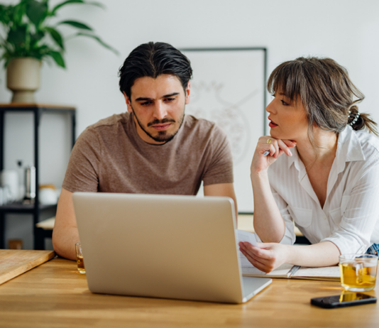 Warum der Weg zum Eigenheim so kompliziert geworden ist Symbolbild für Artikel: Warum der Weg zum Eigenheim so kompliziert geworden ist; Mann und Frau besprechen etwas und sitzen am Laptop