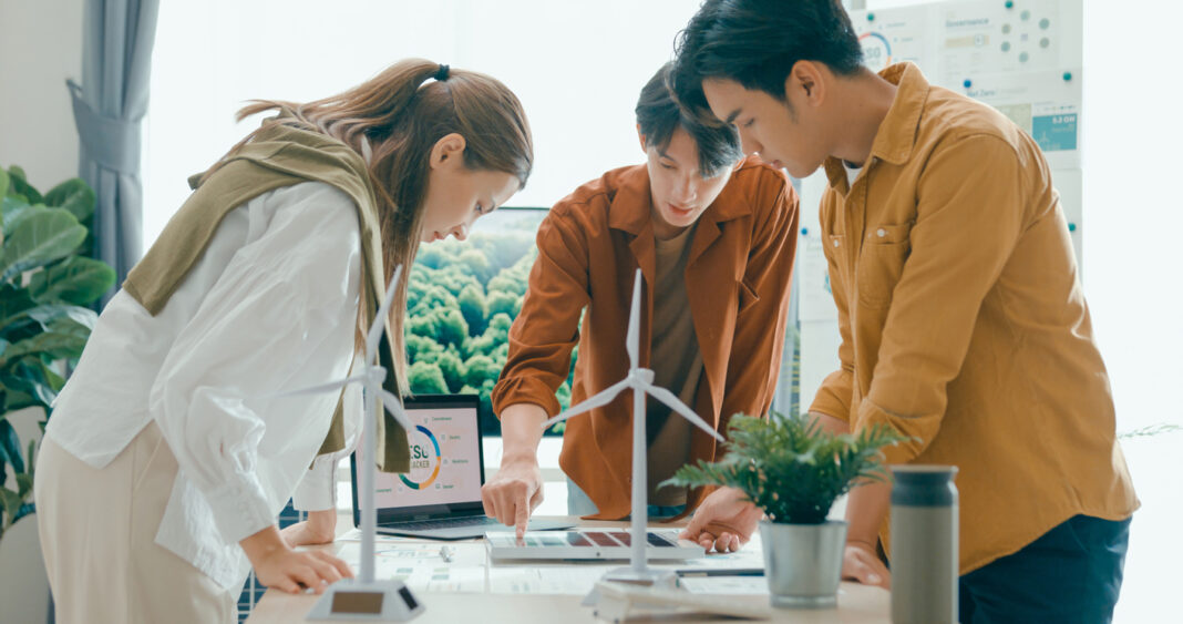 Symbolbild zu Energiewende, 3 Personen stehen um einen Tisch mit Windrädern und planen ein Projekt.