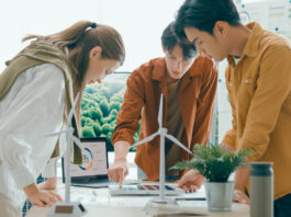 Symbolbild zu Energiewende, 3 Personen stehen um einen Tisch mit Windrädern und planen ein Projekt.