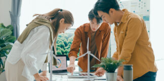 Symbolbild zu Energiewende, 3 Personen stehen um einen Tisch mit Windrädern und planen ein Projekt.