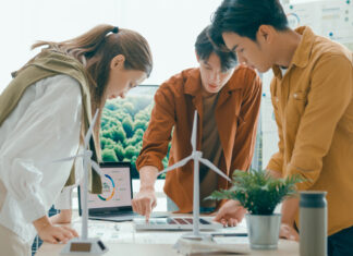 Symbolbild zu Energiewende, 3 Personen stehen um einen Tisch mit Windrädern und planen ein Projekt.