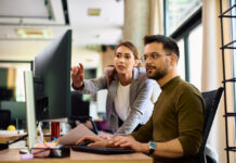 Die nächste KI-Revolution arbeitet unsichtbar Junge Kolleginnen und Kollegen kooperieren bei der Arbeit am Computer im Büro.