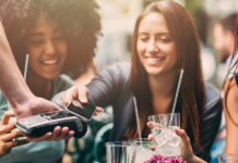Frau, die kontaktlos über ein Smartphone bezahlt.