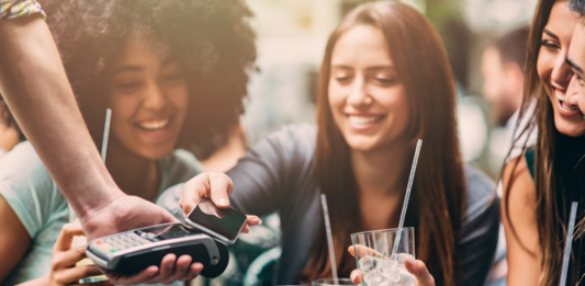 Frau, die kontaktlos über ein Smartphone bezahlt.