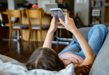 Teenager-Mädchen zu Hause, das sich soziale Medien auf ihrem Handy anschaut